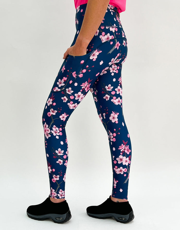 Woman wearing cherry blossom activewear leggings with pockets on dark blue background