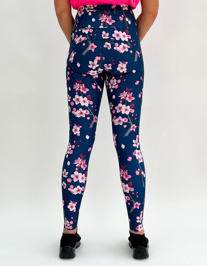 Women's cherry blossom activewear leggings with pink floral pattern on dark blue background and pockets