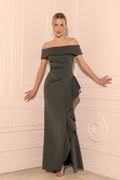 Woman wearing a dark green off-shoulder gown against a white wall.