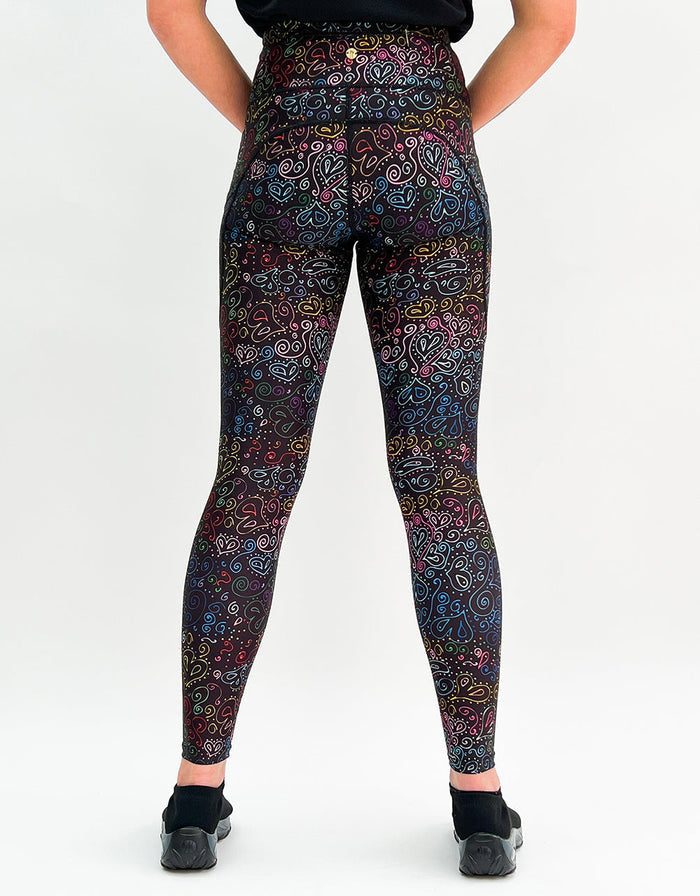 Black gym leggings with vibrant multicolored heart doodle print and side pockets, shown from the back.