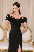 Woman wearing a black off-shoulder dress with floral details in an elegant setting.