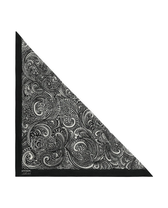 The Stetson Western Paisley Scarf in black from THE GREAT. F26 STETSON features an intricate black and white paisley pattern, folded diagonally to form a triangle with delicate vintage-inspired swirling designs and a small logo in one corner. Part of the exclusive Stetson collaboration.