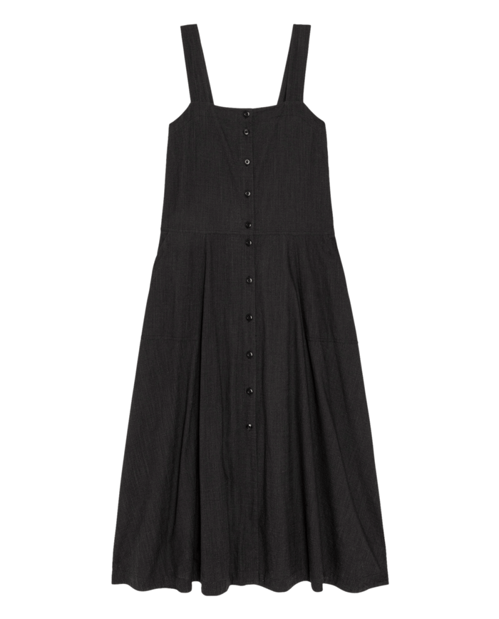 THE GREAT. SU26 The Apron Dress in black, sleeveless with wide shoulder straps and front button-down closure, shown flat on a white background.
