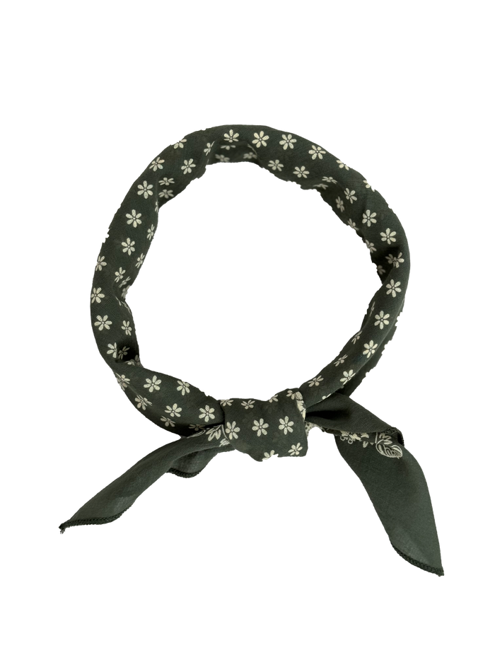 The Bandana by THE GREAT. SP24 D2, in Small and Army Green, showcases a charming white floral pattern. Expertly tied in a loop with two ends hanging down, this piece is crafted from 100% cotton, delivering the vintage feel of classic handkerchiefs along with an ultra-soft touch for everyday comfort.