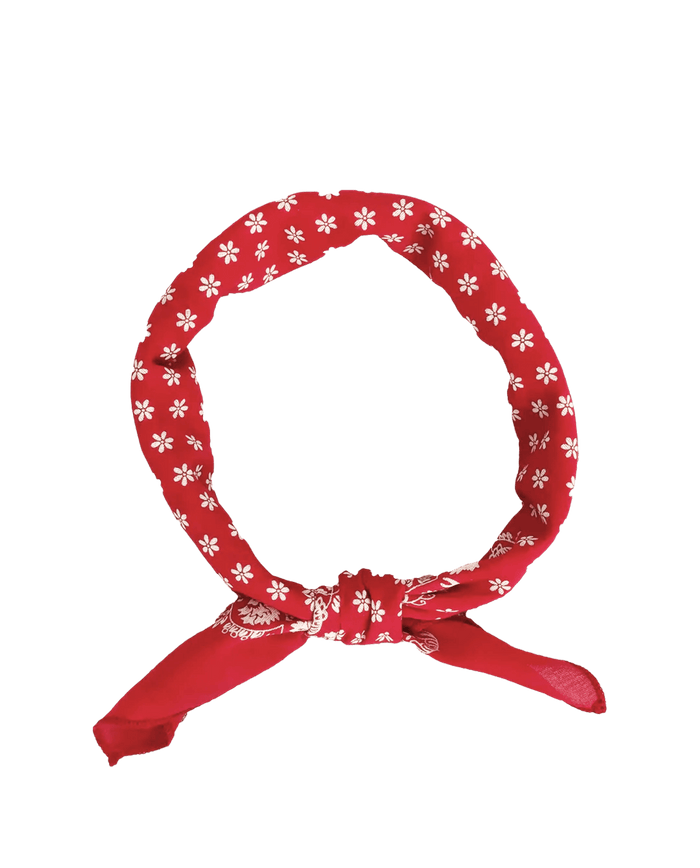 The Bandana. -- Small -- Bright Red by THE GREAT. CARRYOVER, crafted from ultra-soft cotton, showcases a classic bright red hue with white floral patterns and is styled in a simple knot at the bottom, set against a plain white background.