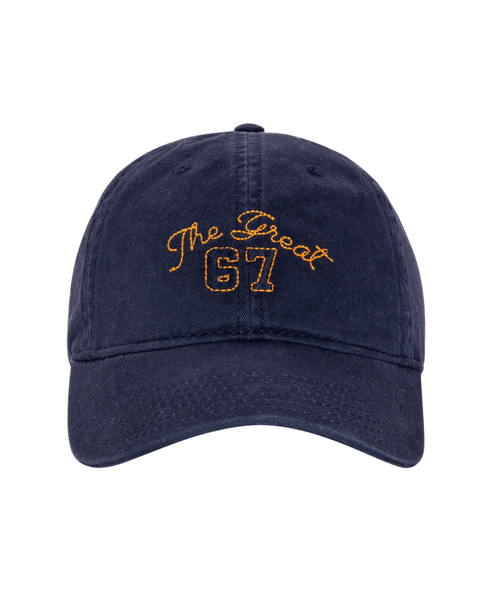 The Baseball Hat by THE GREAT. PF26 in navy features yellow "The Great 67" embroidery on the front, adding a sporty touch to any outfit.