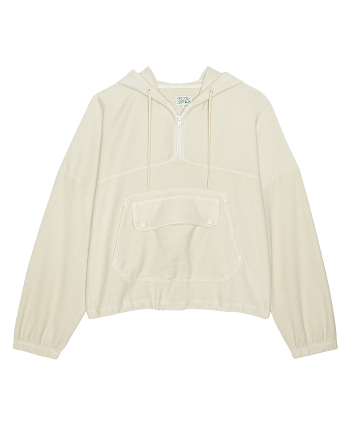 THE GREAT. SP26 TGO The Basecamp Pullover—Oatmilk features a hood, half-zip, front kangaroo pocket with buttoned flap, and elastic cuffs for stylish outdoor wear.