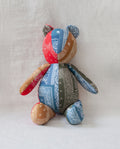 The Bear. -- Multi by THE GREAT. is an upright patchwork cotton bear crafted from red, blue, green, and tan bandana fabric, set against a light background for a vintage Western-inspired heirloom look.