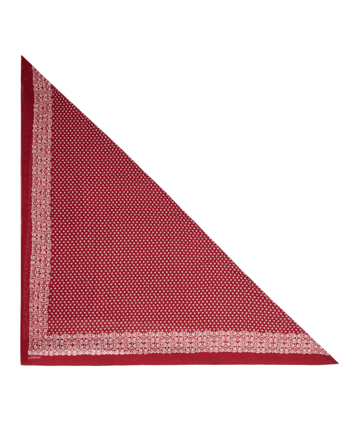 A maroon bandana from THE GREAT., called The Big Bandana, is folded into a triangle and displayed on a plain white background. It showcases a small white dotted pattern with a white floral border.