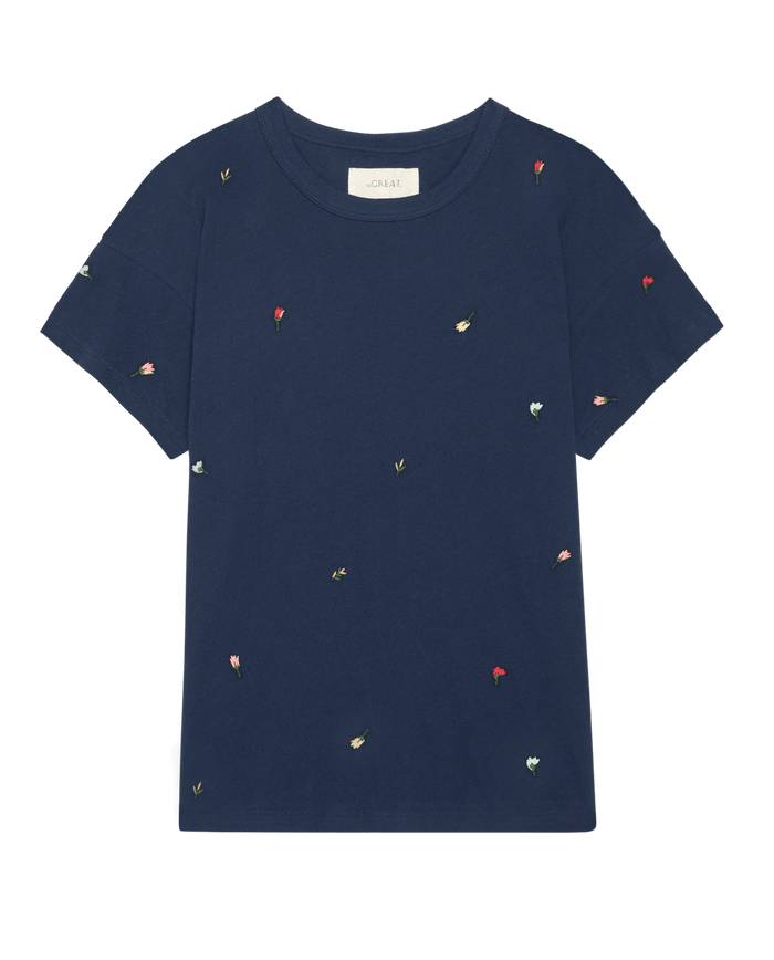 The Boxy Crew W/ Tossed Floral Emb. in navy by THE GREAT. SU26 features a boxy silhouette and scattered, multicolor floral embroidery on the front, inspired by vintage tees and handcrafted Los Angeles style.