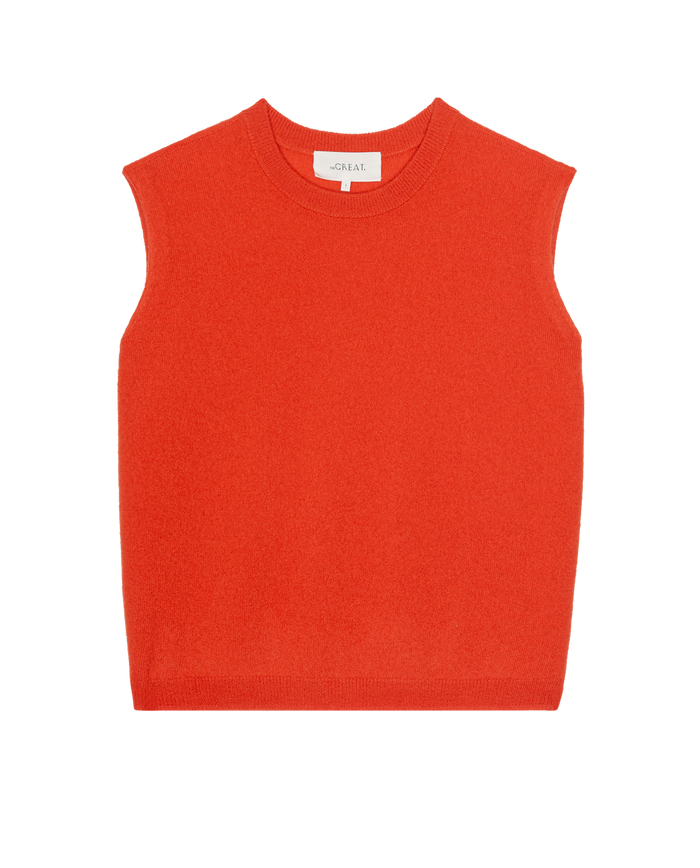 The Cashmere Pullover Vest by THE GREAT. PS26 in Hot Orange is a sleeveless knit style laid flat on a white background, bringing vintage menswear vibes.