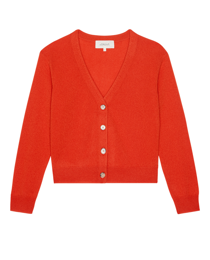 The Cashmere Tiny V Neck Cardigan by THE GREAT. PS26 in Hot Orange, featuring long sleeves and four front buttons, is displayed flat on a white background.