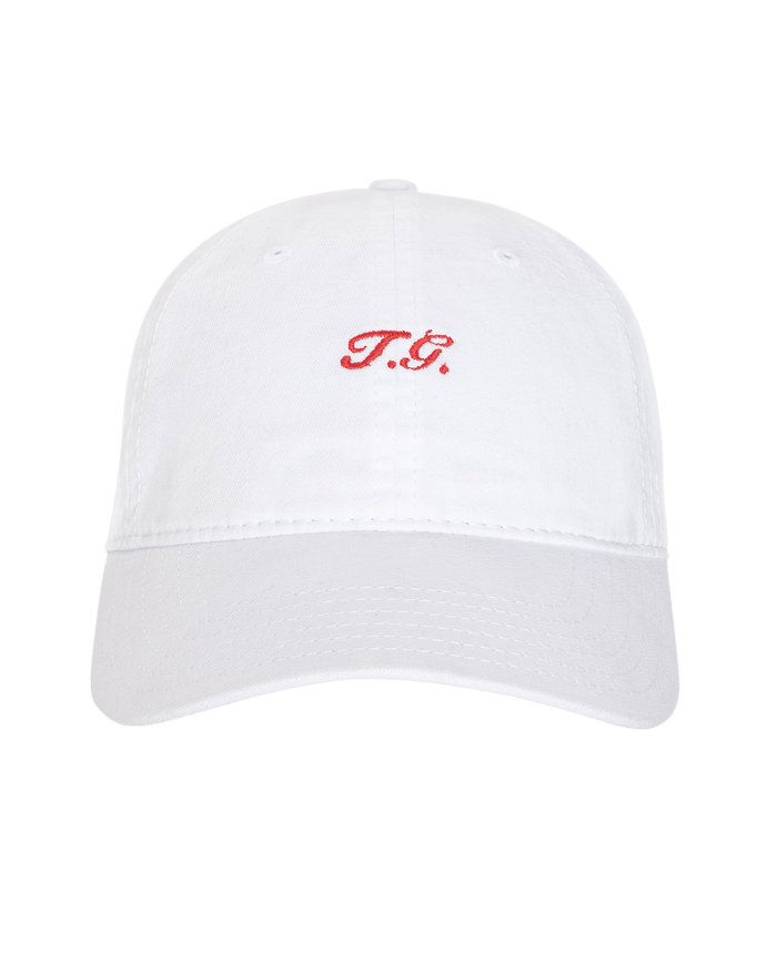 The Baseball Hat in white by THE GREAT. SU26 features "T.G." embroidered in red on the front, displayed on a plain white background—ideal for everyday wear or your next game.