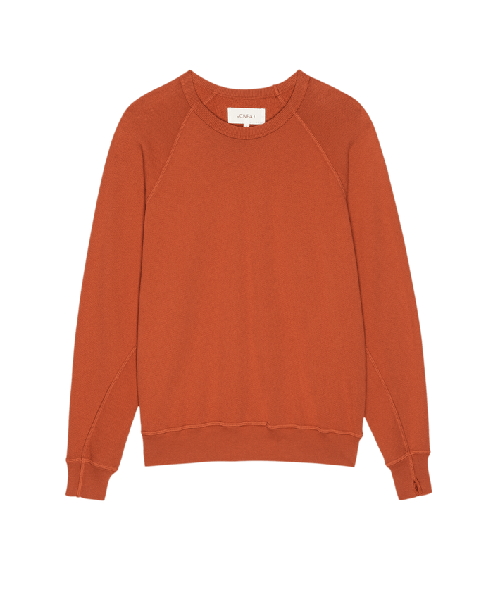 The College Sweatshirt. Solid -- Desert Clay by THE GREAT. SU25 SEASONAL KNITS is a classic crewneck, long-sleeve essential in rust, laid flat on white—ideal for comfortable, stylish college wear.