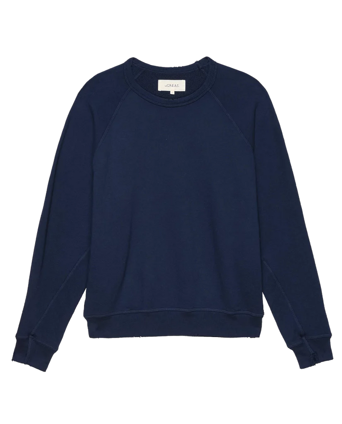 A handcrafted, plain navy blue crewneck sweatshirt with ribbed cuffs and hem, lying flat. This is The College Sweatshirt in True Navy by THE GREAT., part of their FALL 23 KNITS collection.