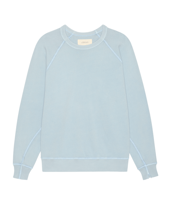 The College Sweatshirt in Whisper Blue by THE GREAT. SP26 SEASONAL CORE features an oversized fit, raglan sleeves, and ribbed cuffs, handcrafted in Los Angeles and shown laid flat on a white background.