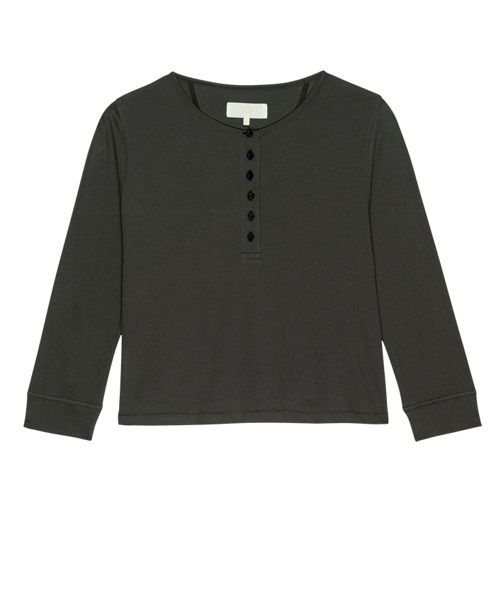 The Crop Sleep Henley by THE GREAT. FALL 24 SLEEP is a long-sleeved, washed black henley shirt featuring a round neckline and six black buttons on the front, crafted from cozy jersey fabric.