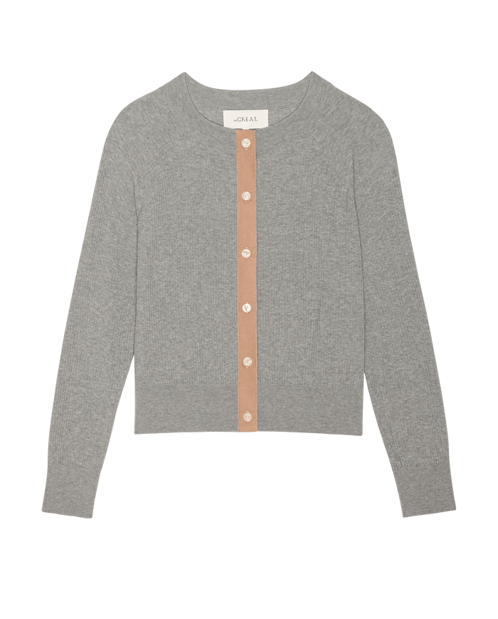 The Dainty Cardigan by THE GREAT. SP26 D2 in Heather Grey features long sleeves, a round neckline, a beige button placket with white buttons—perfect as a lightweight women’s sweater, shown on a white background.
