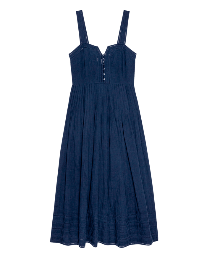 The Day Break Dress by THE GREAT. SU26 is a navy sleeveless midi with wide straps, a fitted bodice with button accents, and a pleated skirt.
