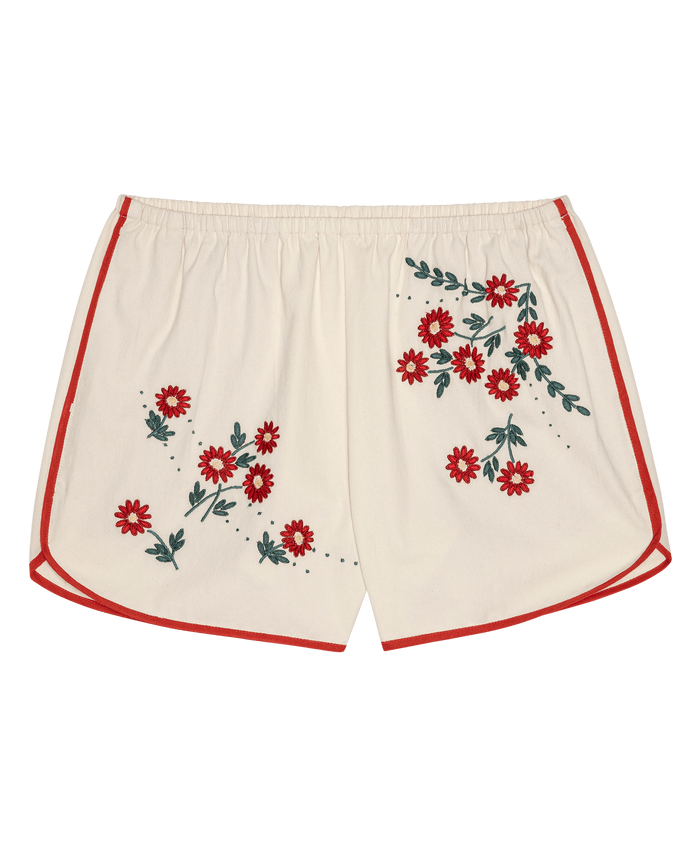 THE GREAT. SU26 The Dolphin Short in Natural With Field Floral Emb features cream-colored fabric with red trim and embroidered red flowers and green leaves on the front.