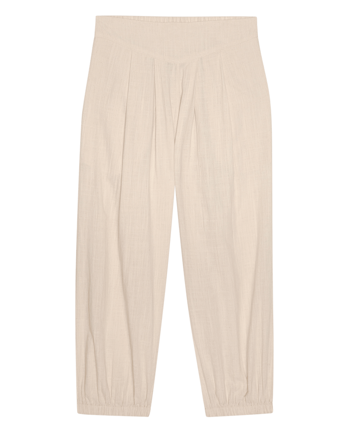 The Elastic Blouson Pant in Natural by THE GREAT. SU26 features a high waist, linen fabric, front pleats, tapered legs, and elastic ankle cuffs, shown laid flat on a white background.