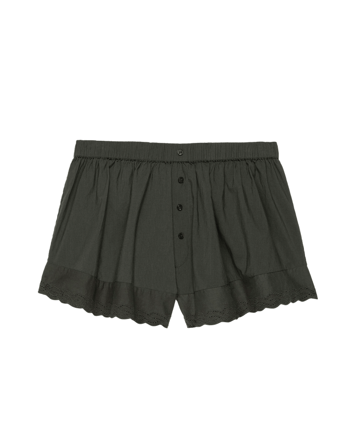 The Eyelet Tap Short by THE GREAT. PS25 SLEEP features a button front, elastic waistband, and scalloped Victorian-inspired eyelet lace trim on a plain black background, crafted from soft cotton voile.