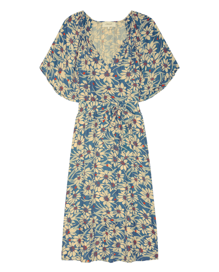 The Fairground Dress by THE GREAT. SP26 D2 in Blue Scattered Bloom features a knee-length cut, short sleeves, V-neck, tie waist, and white floral print—making it an easy pullover for effortless style.