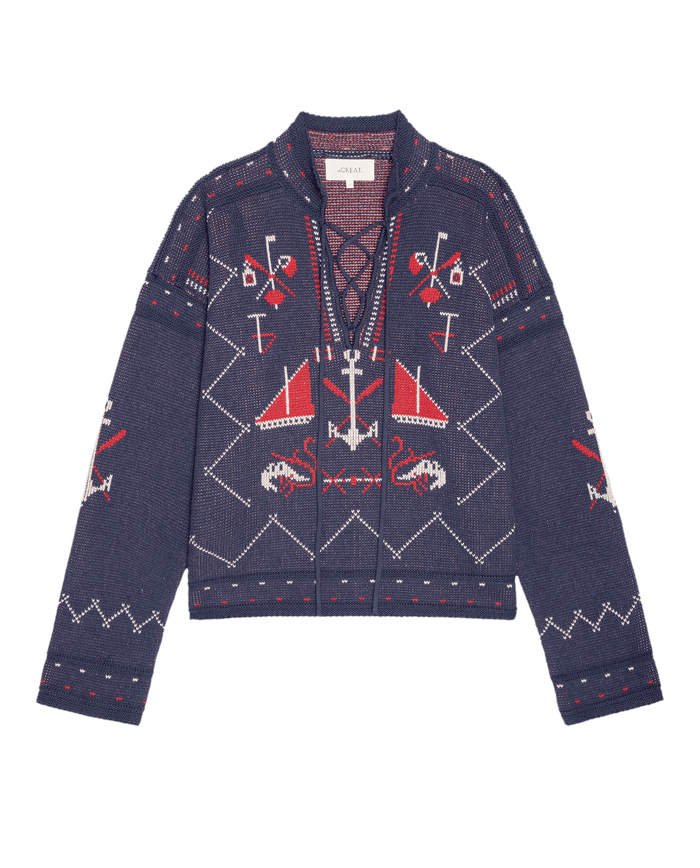 The Fisherman Laceup Pullover by THE GREAT. SU26 in navy features red and white nautical and geometric patterns with anchors, crabs, boats, and crossed oars on the front and sleeves.