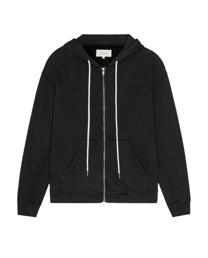 The Fleece Campus Hoodie in Almost Black from THE GREAT. F26 D1 FLEECE BACK KNITS features a zip-up front, front pockets, white drawstrings, and a hood, all crafted from a soft fleece cotton-blend for comfort—presented on a plain white background.