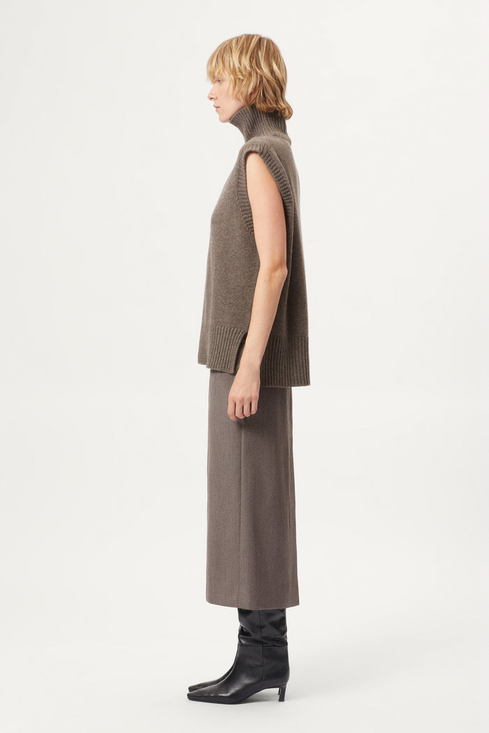 woman wearing a wool brown sleeveless high neck knitted top and skirt set on a white background