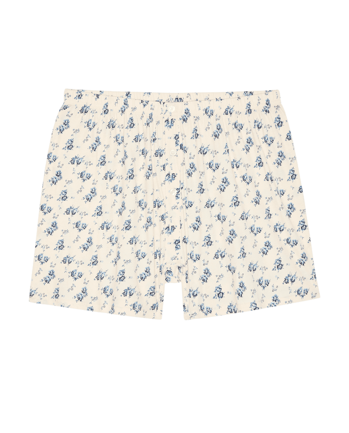 The Jersey Boxer Short in Indigo Rose by The Great. SP26 Sleep features cream-colored cotton jersey with a blue floral pattern, shown flat on a white background.