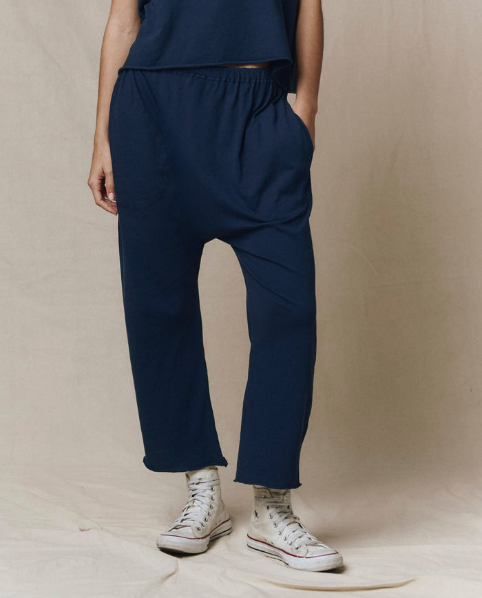A person models THE GREAT. CORE KNITS The Jersey Crop Pant in True Navy, paired with a matching top and white high-top sneakers, shown from the waist down against a plain beige background.