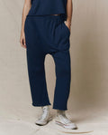 A person models THE GREAT. CORE KNITS The Jersey Crop Pant in True Navy, paired with a matching top and white high-top sneakers, shown from the waist down against a plain beige background.