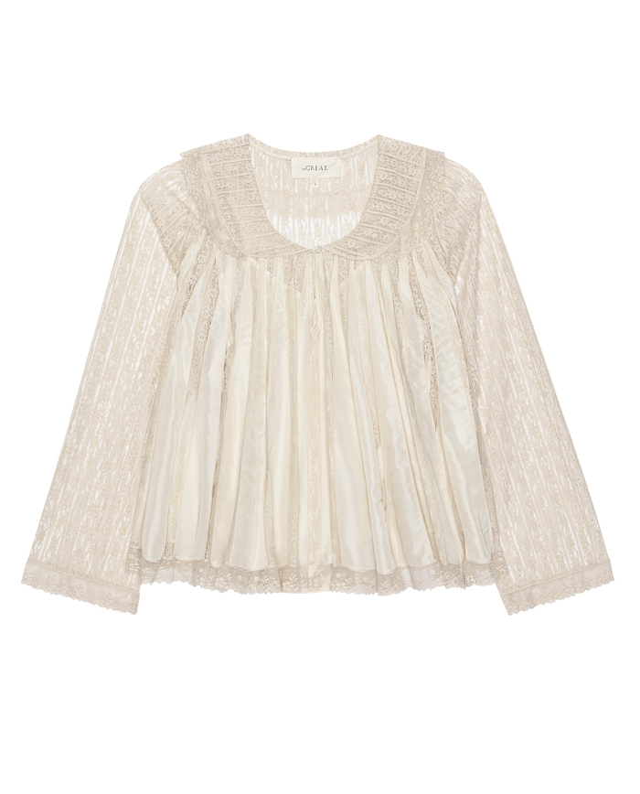 The Keepsake Lace Collared Top in cream from THE GREAT. H25 COLLECTION features sheer ivory lace, long sleeves, pleated bodice, a round neckline with delicate detailing. Shown on a plain white background.