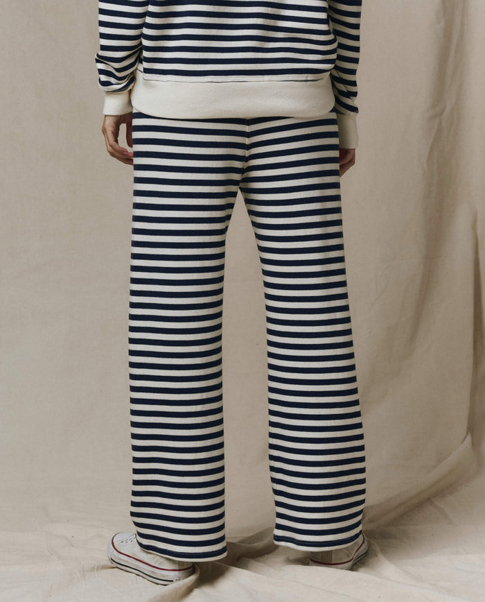 Back view of person standing on beige surface, wearing THE GREAT. The Lap Sweatpant in Navy Sailor Stripe (SP26 SEASONAL CORE) with a matching top and white sneakers. Handcrafted Los Angeles style; photo shows look from shoulders down.