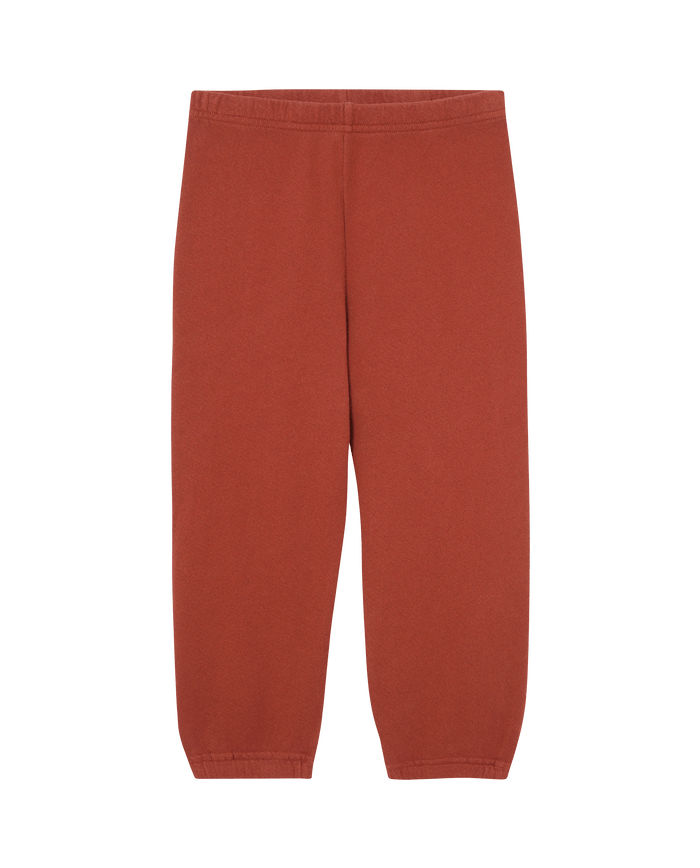 The Little Stadium Sweatpant. Solid -- Brick by THE GREAT. F25 LITTLES features a loose, high-waisted fit with an elastic waistband in a rust color, inspired by vintage athletic wear and shown against a white background.
