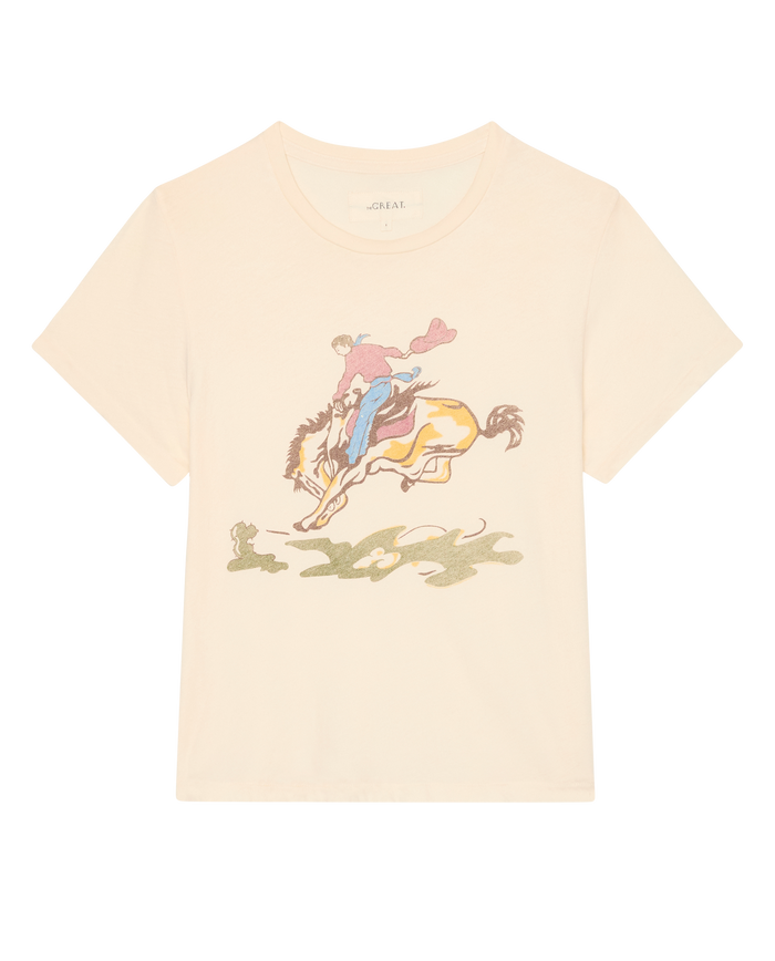 The Little Tee W/ Rider Graphic by THE GREAT. SP26 D1, in washed white, features a cowboy on horseback with a subtle shadowy ground below.