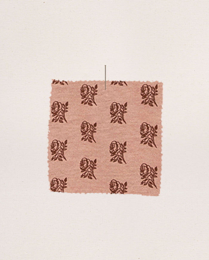 A square of pink fabric printed with brown roses—a nod to the cozy elegance of THE GREAT. F26 SLEEP’s The Long John. -- Rose Print—is pinned against a plain white background.