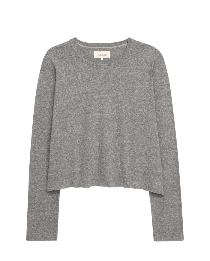 The Long Sleeve Crop Tee by THE GREAT. CORE KNITS in Heather Grey features a round neckline and long sleeves, ideal for layering. Its simple design contrasts beautifully with the white background.