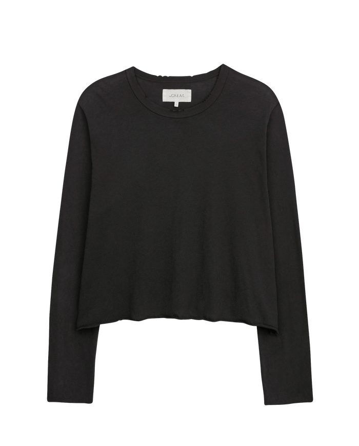 The Long Sleeve Crop Tee in Washed Black by THE GREAT. CORE KNITS is a black, long-sleeve cropped tee with a raw hem, ideal for layering, shown on a plain white background.