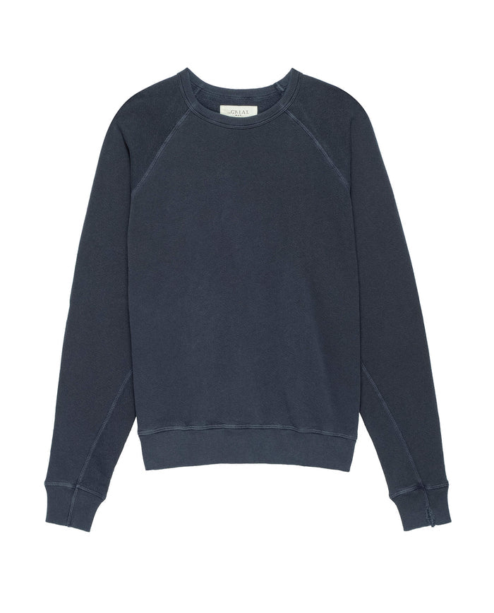 The Men's College Sweatshirt in Washed Navy by THE GREAT. MAN is a vintage, dark gray garment made from 100% cotton, featuring long sleeves with ribbed cuffs and hem.
