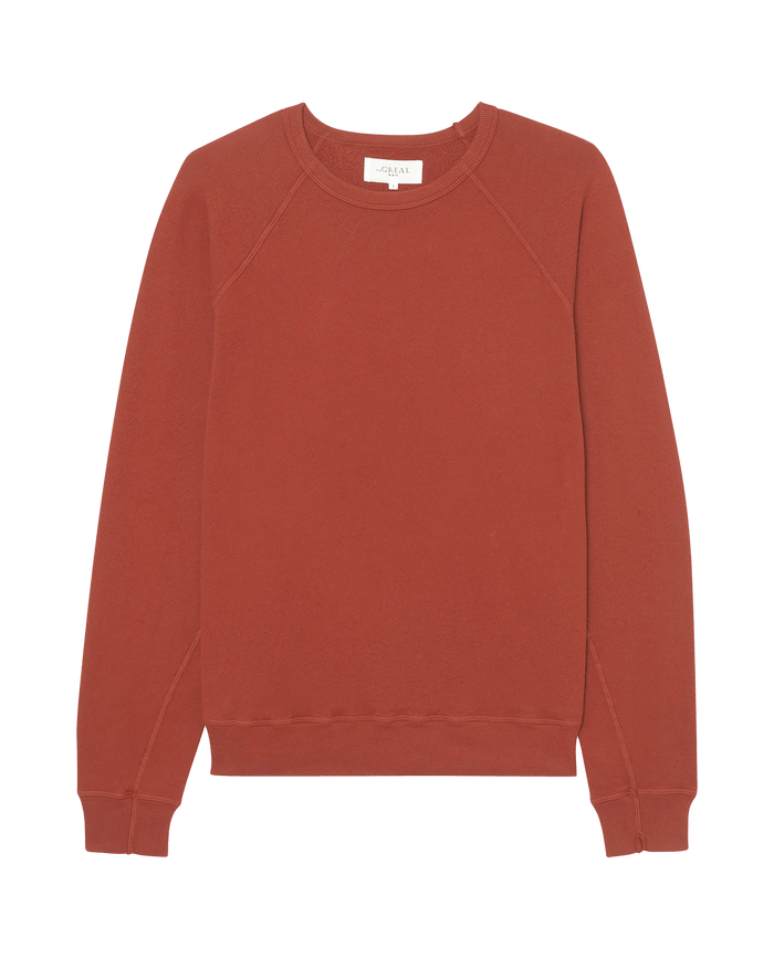 The Men's College Sweatshirt by THE GREAT. F25 MENS in Solid Brick is a comfortable, plain long-sleeve crew neck displayed flat on white—ideal for fans of vintage college sweatshirts.
