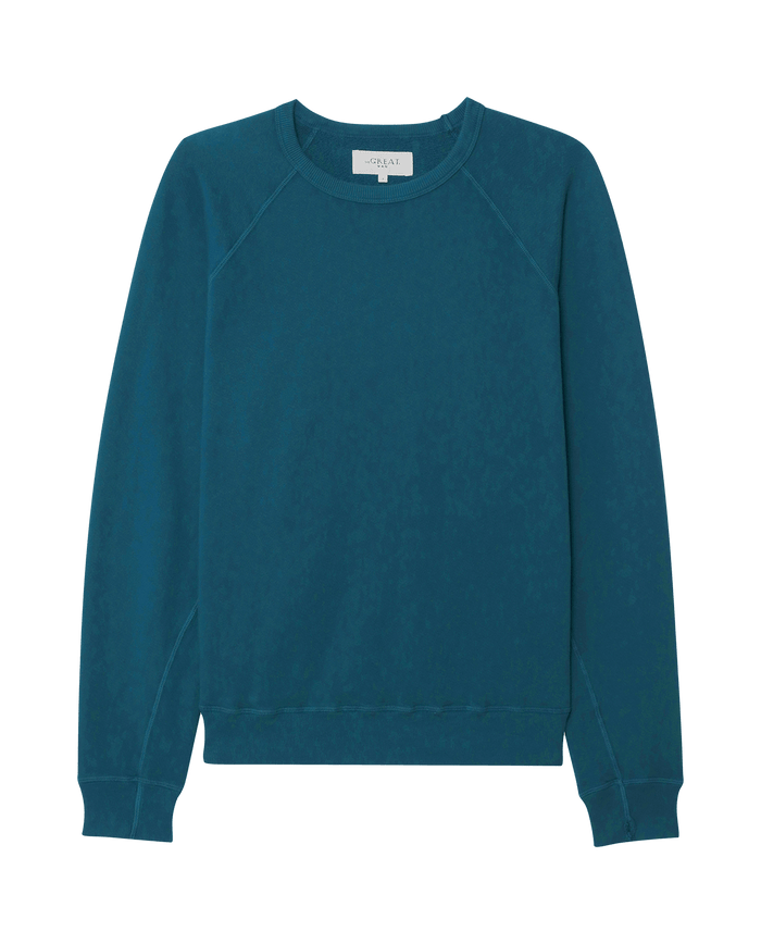 The Men's College Sweatshirt in Dark Slate by THE GREAT. F25 MENS, a vintage-inspired, teal blue long-sleeve crewneck, is laid flat on a white background.