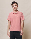 A person wearing The Men's Lacrosse Polo in Sun Cherry Stripe by THE GREAT. SP25 POLO LOUNGE MEN stands before a beige backdrop.