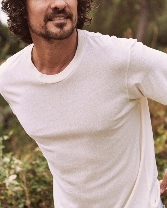 Man with curly hair wearing a Washed White Men's Slim Tee by THE GREAT. HOL 21 MENS standing outdoors.