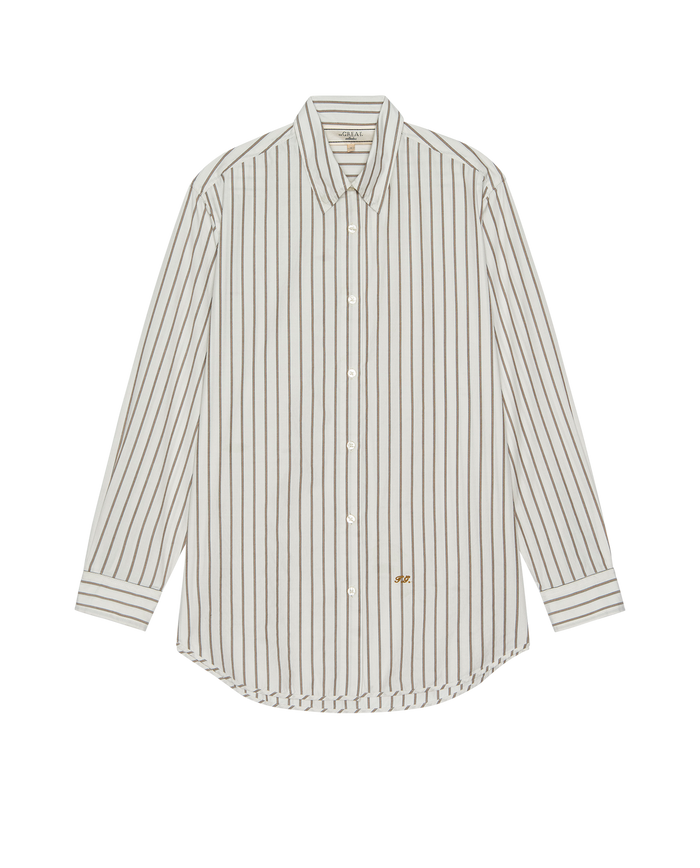 The Menswear Button Up – Ivy League Stripe by THE GREAT. PS26 COLLECTORS is a long-sleeve shirt with vertical black-on-white pinstripes, a sharp collar, and a small embroidered logo near the hem for classic style.