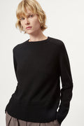 Woman wearing a black merino  sweater on a plain background