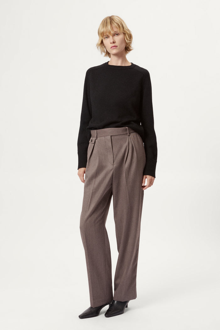 Woman wearing a black merino  sweater on a plain background