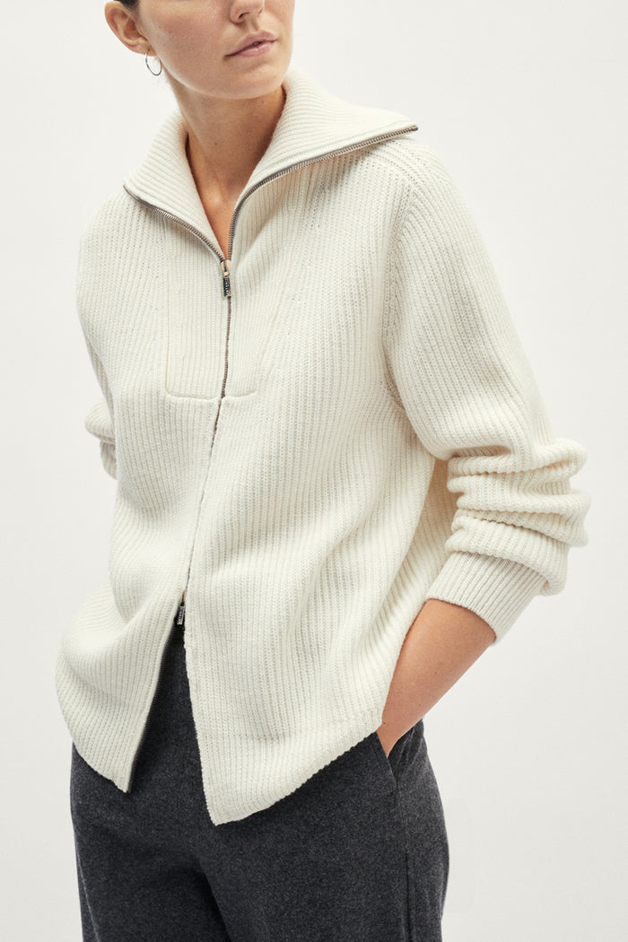 Person wearing a cream-colored sweater with a white background