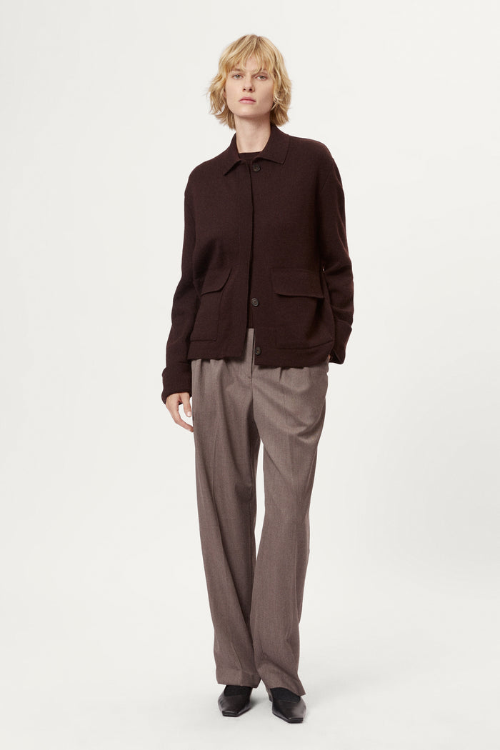 Woman wearing a dark brown jacket and pants on a white background